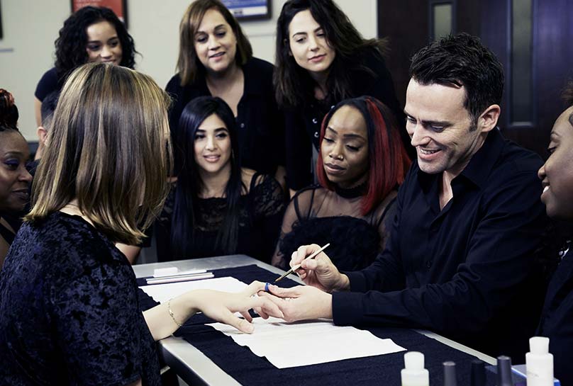 A leader demonstrating a nail technique to many students