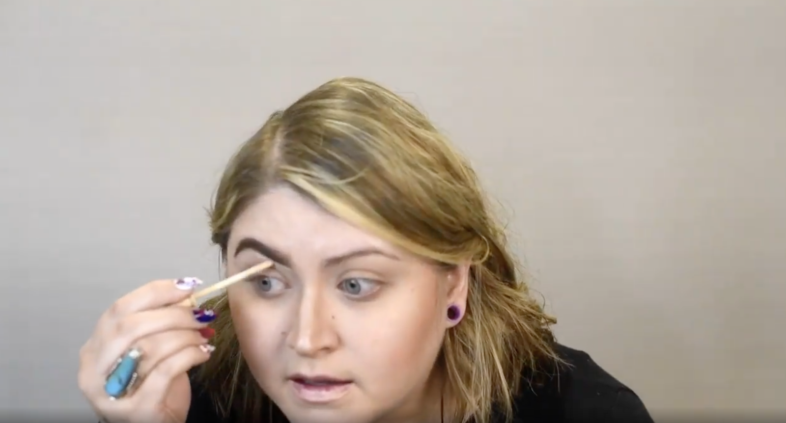 Instructor cleaning up with concealer underneath the brows